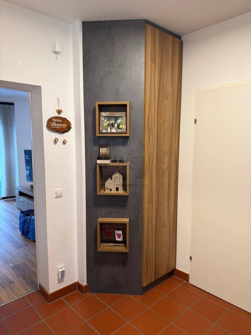 Eingangsbereich mit Terrakotta-Fliesenboden und dekorativer Holzwand im modernen Stil.