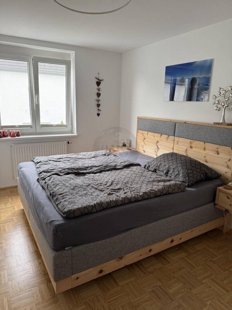 Schlafzimmer mit hellem Holzparkett und einem gemütlichen Bett mit Holzrahmen.