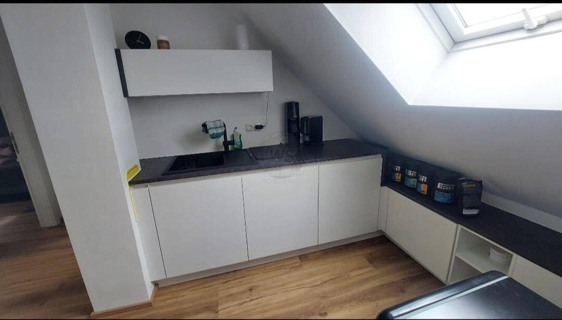Kleine Küchenzeile im Dachgeschoss mit Dachfenster und modernen Schränken.