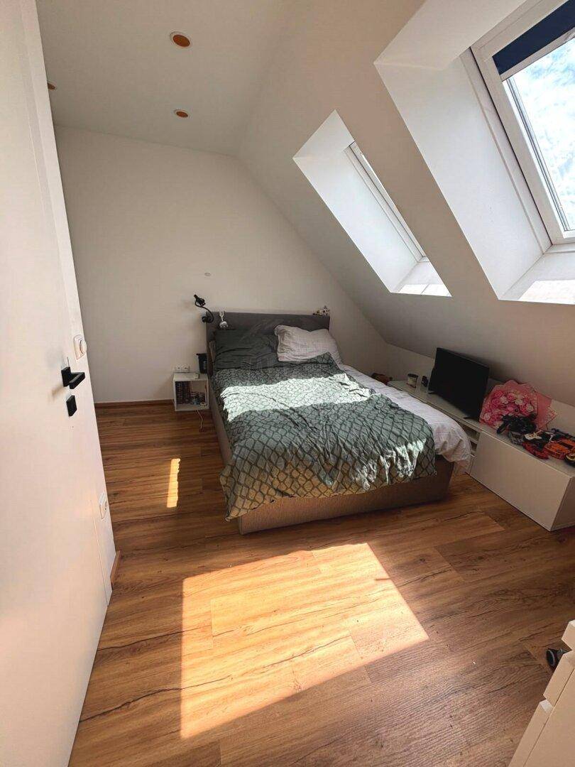 Helles Schlafzimmer im Dachgeschoss mit zwei Dachfenstern und Laminatboden.