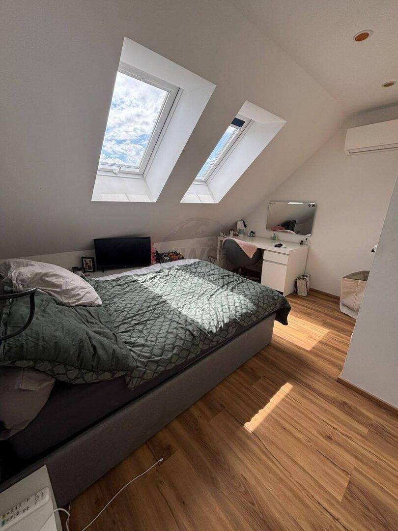 Geräumiges Schlafzimmer im Dachgeschoss mit Schreibtisch, Bett und zwei großen Dachfenstern.