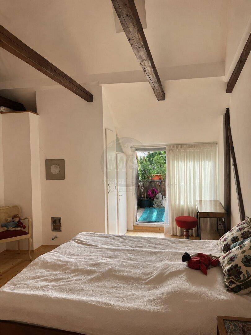 Schlafzimmer mit Holzbalken und Zugang zu einem Außenbereich mit kleinem Pool.