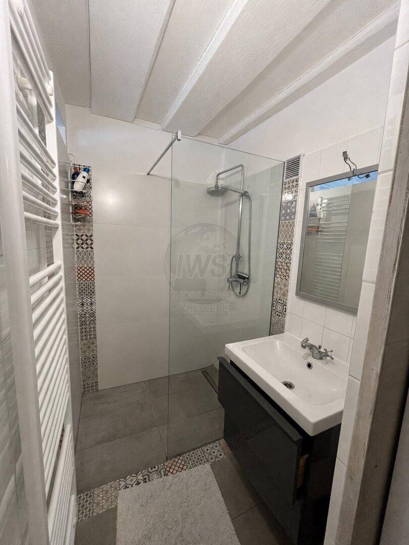Modernes Badezimmer mit begehbarer Dusche, Einzelwaschbecken und gemusterten Fliesen.