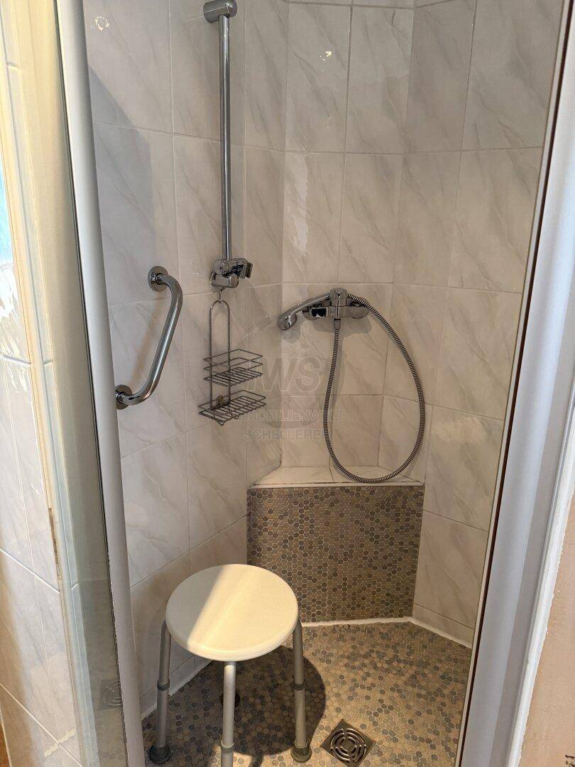 Barrierefreie Dusche mit Haltegriffen und einem Duschhocker für Komfort und Sicherheit.