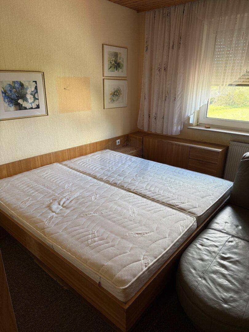 Schlafzimmer mit zwei Einzelbetten, Holzvertäfelung und einem Fenster mit Vorhängen.