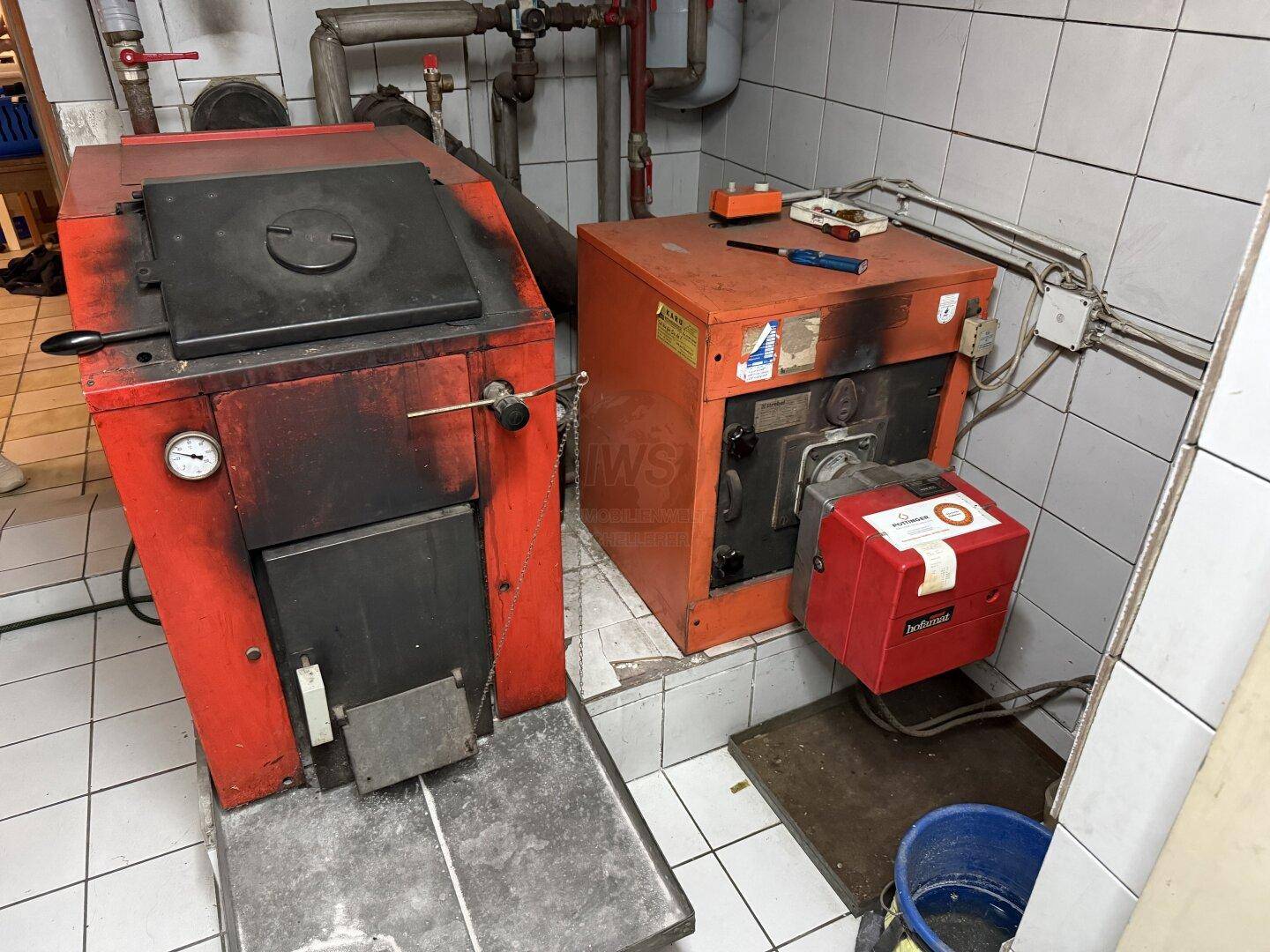 Heizungsraum im Keller mit zwei älteren Heizkesseln und sichtbaren Rohren.