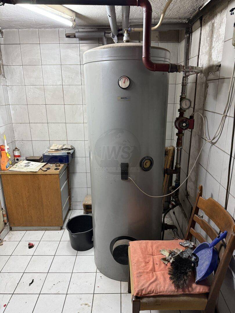 Kellerraum mit großem Warmwasserspeicher und Fliesenboden, als Abstellraum genutzt.