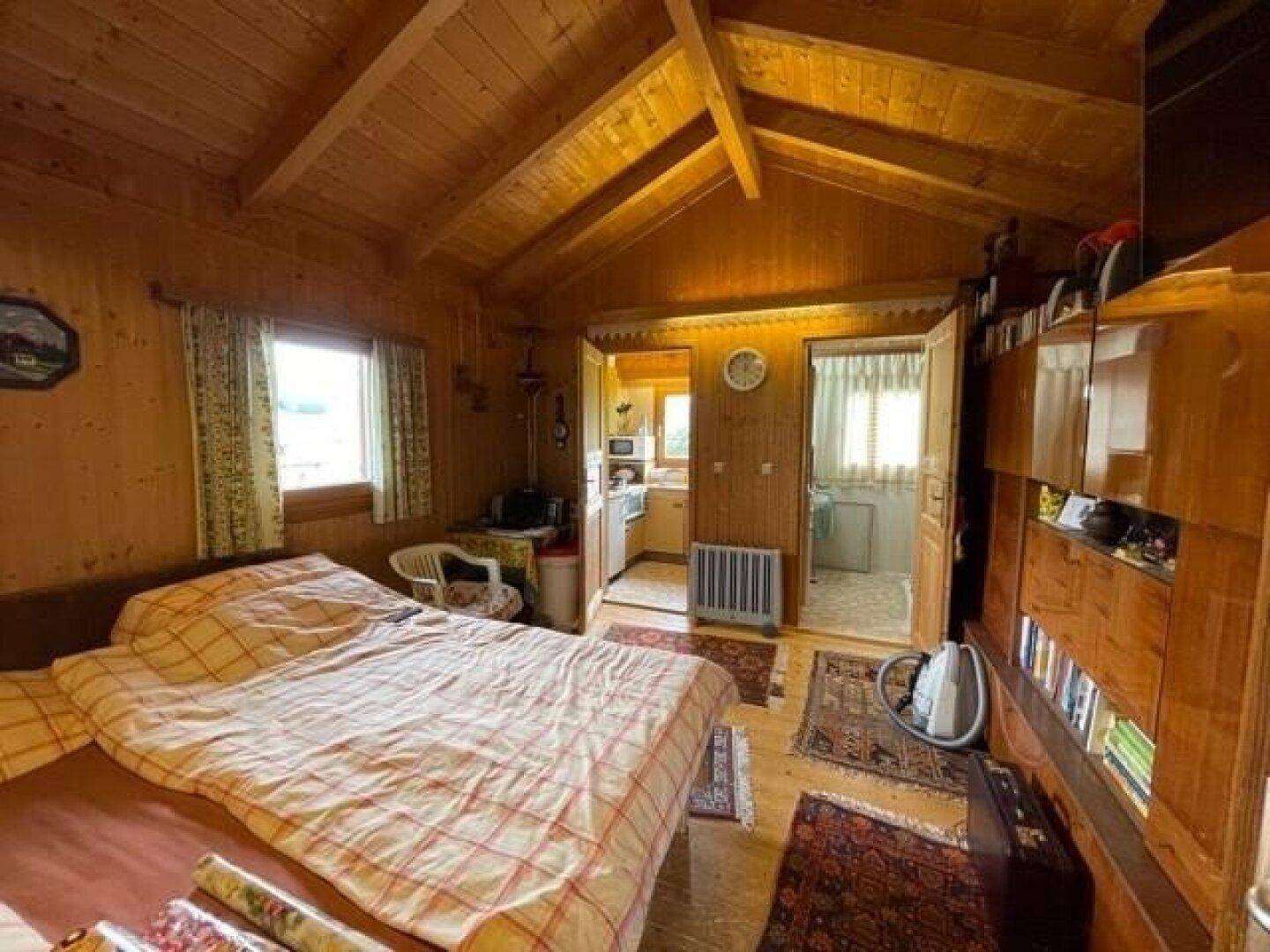 Gemütliches Schlafzimmer mit Holzvertäfelung, sichtbaren Dachbalken und rustikalem Charme.
