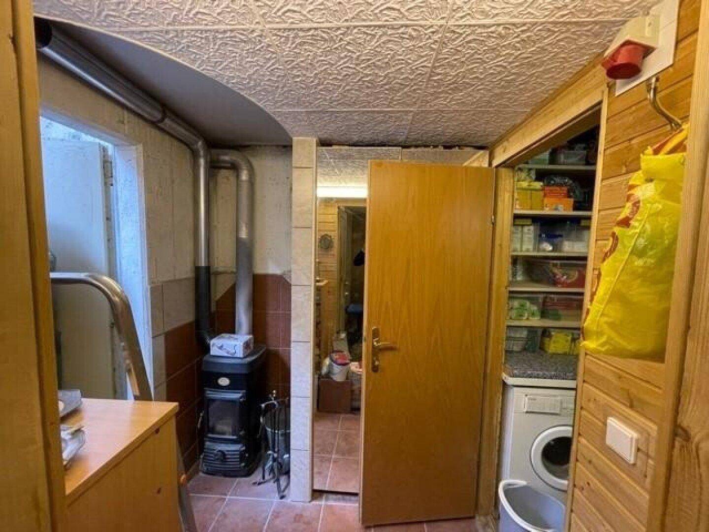 Praktischer Hauswirtschaftsraum im Untergeschoss mit Holzofen, Waschmaschine und Stauraum.