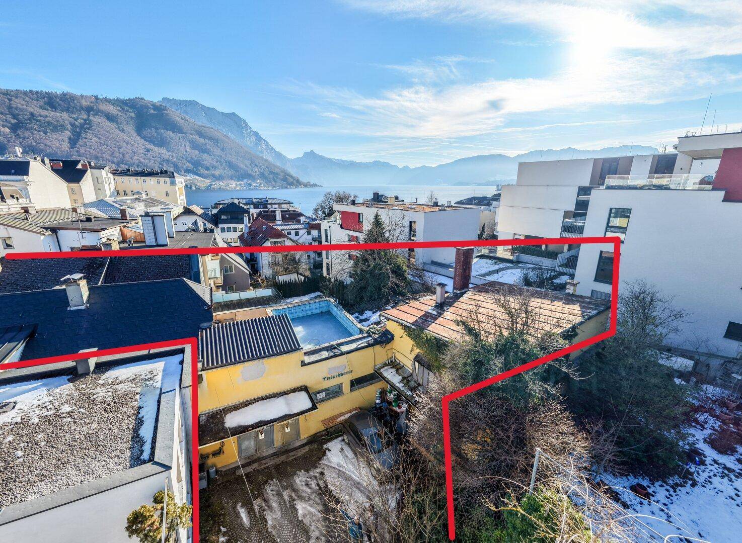 Luftaufnahme eines Anwesens mit Gebäuden, Pool und malerischem See- und Bergblick.