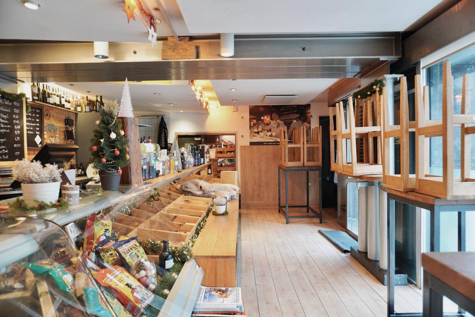 Innenansicht eines Ladengeschäfts mit Theke, Weinregalen und festlicher Dekoration.