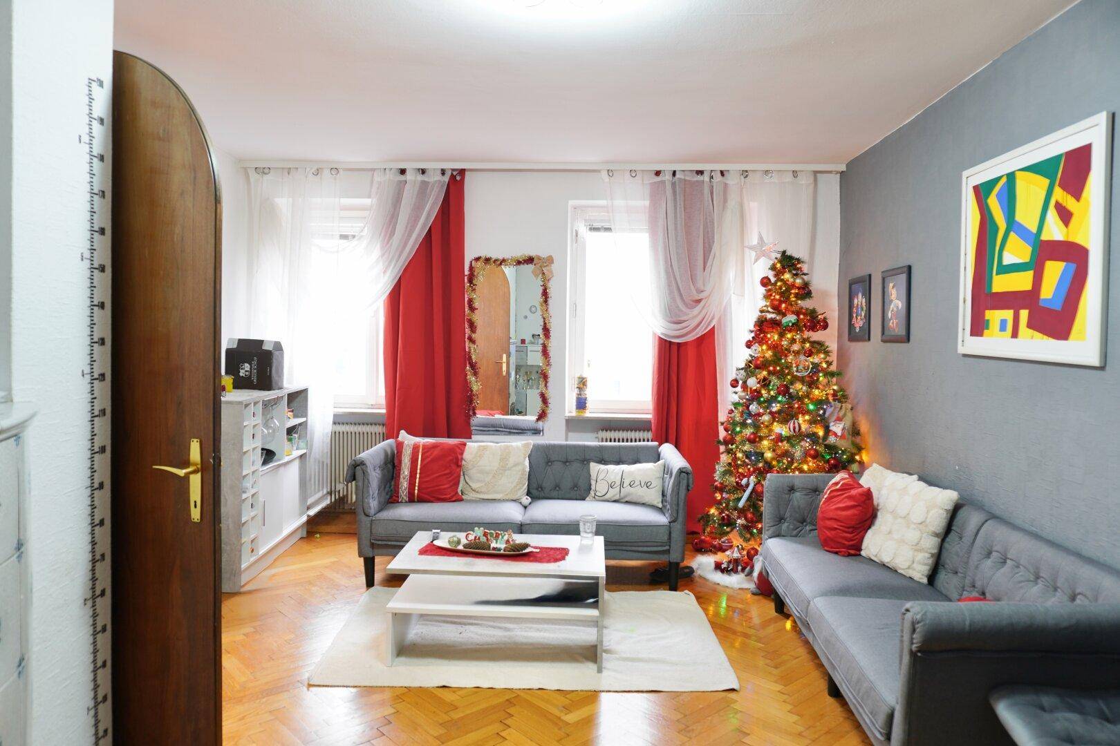 Helles Wohnzimmer mit zwei Sofas, festlichem Weihnachtsbaum und Parkettboden.