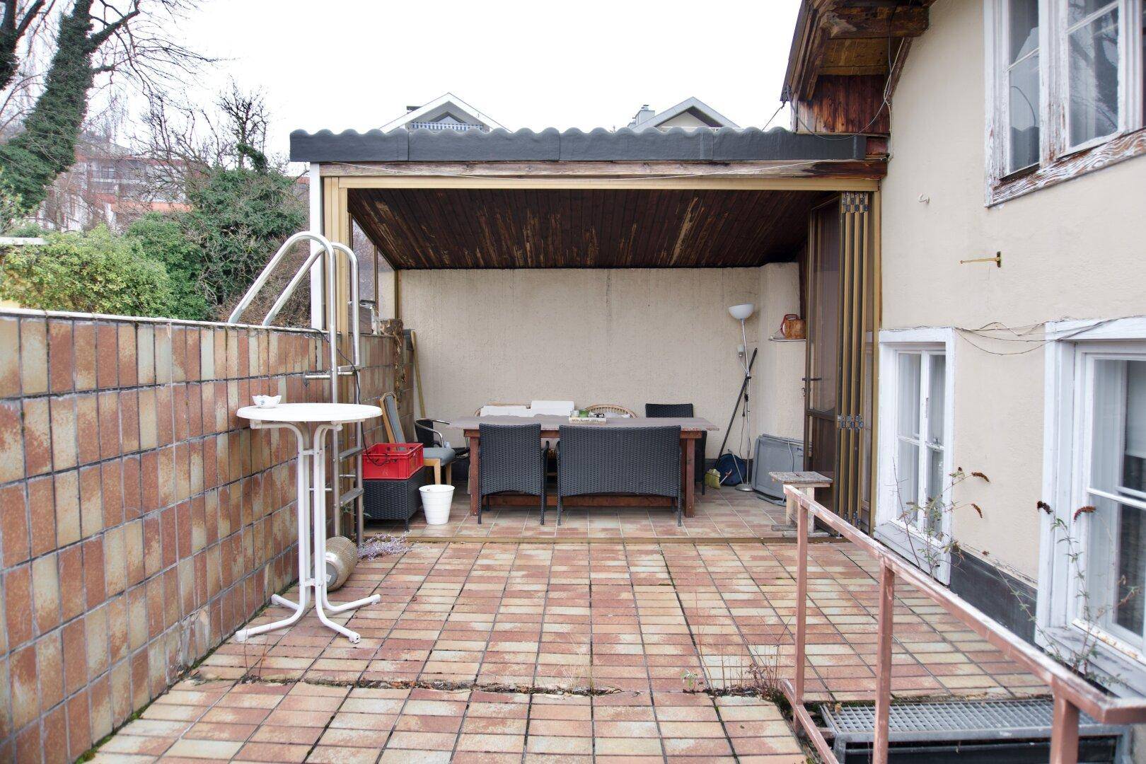 Geflieste Terrasse mit überdachtem Sitzbereich und Zugang zu einem kleinen Pool.