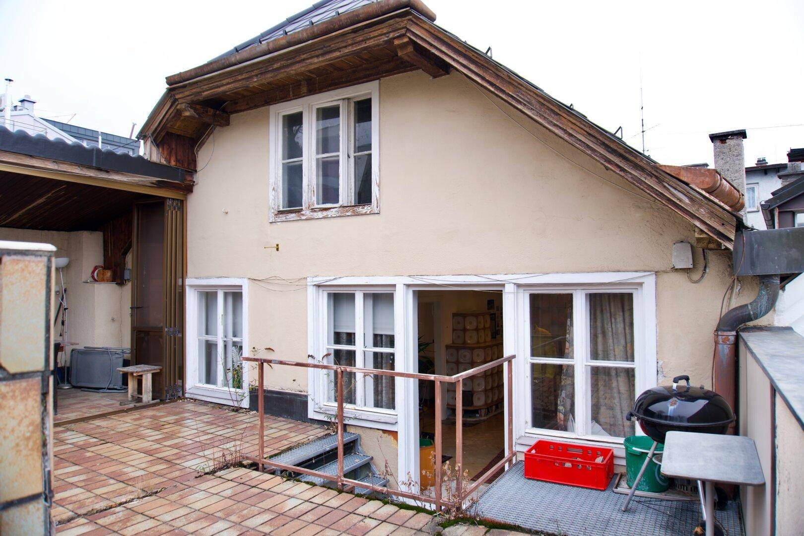 Außenansicht des Hauses von der Terrasse aus mit Grillplatz und Fenstern.
