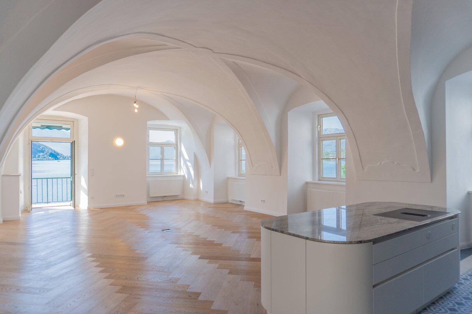 Heller, offener Wohnbereich mit beeindruckenden Gewölbedecken, Fischgrätparkett und Seeblick.