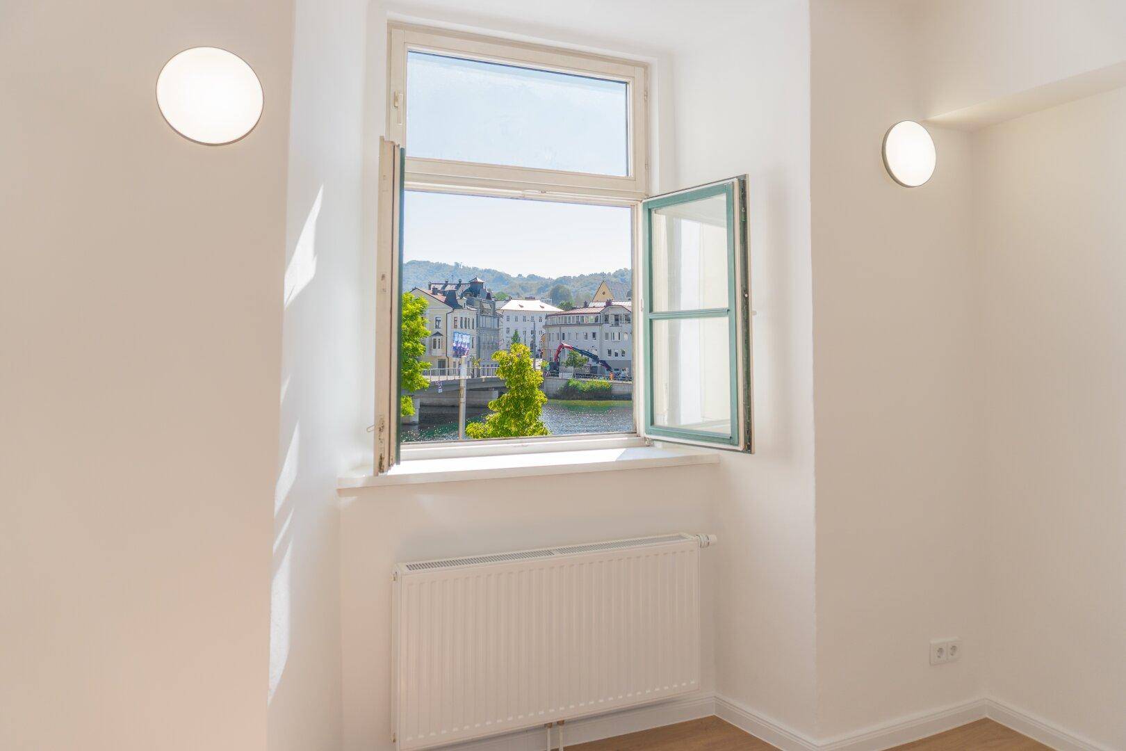 Helles Zimmer mit Fenster und Blick auf den Fluss und die Stadt, ausgestattet mit Heizkörper.