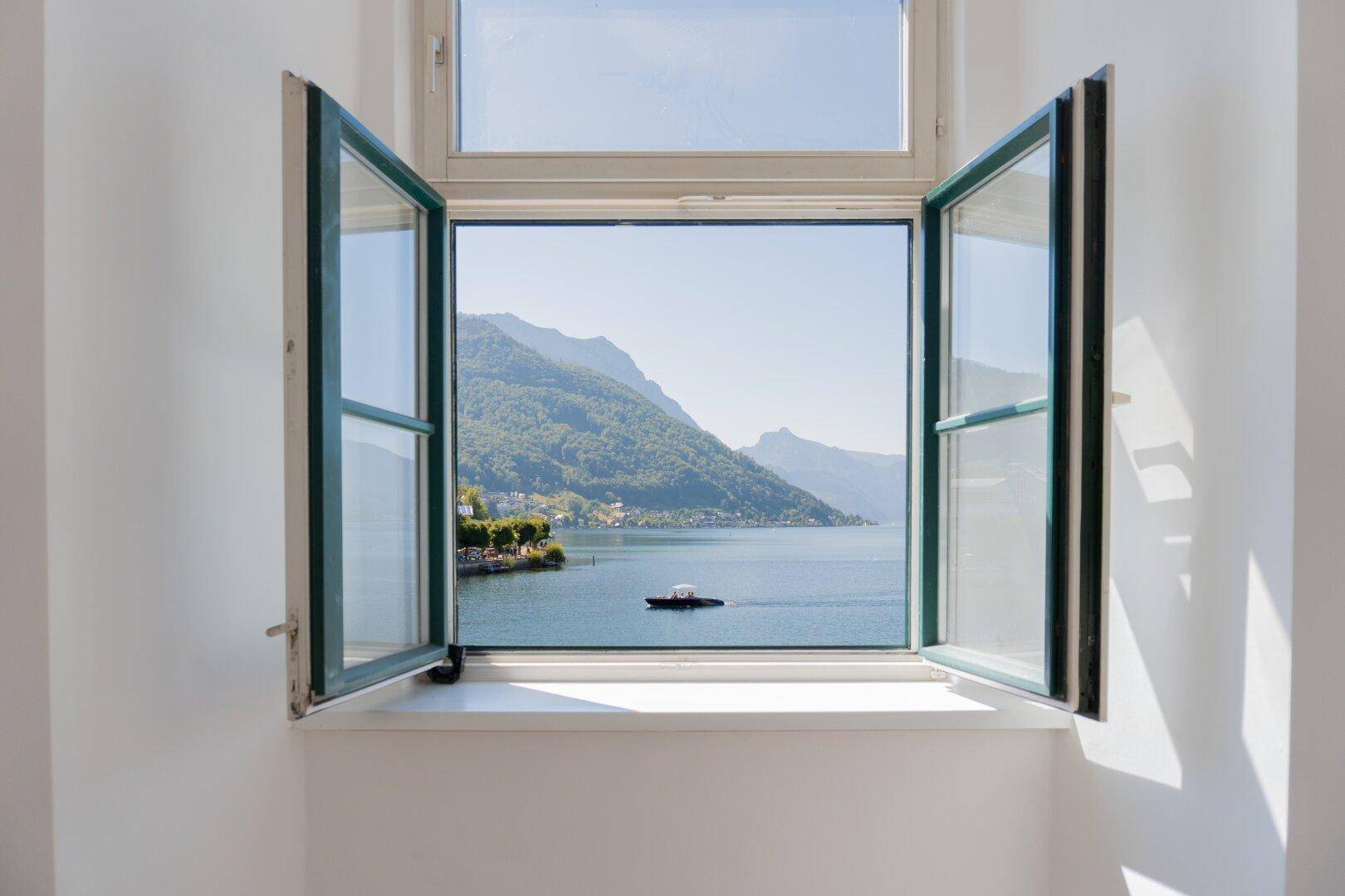 Fenster mit malerischem Blick auf den See und die umliegenden Berge.