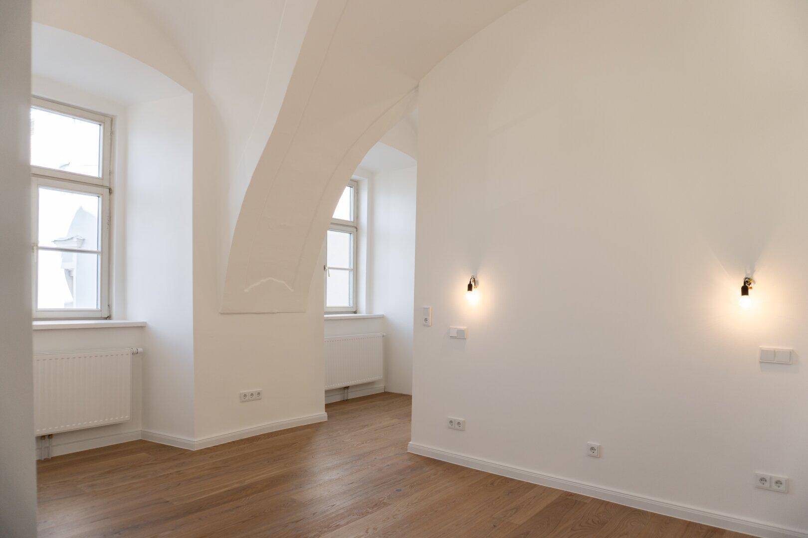 Heller Wohnraum mit beeindruckenden Gewölbedecken und Holzboden, bereit zur Einrichtung.