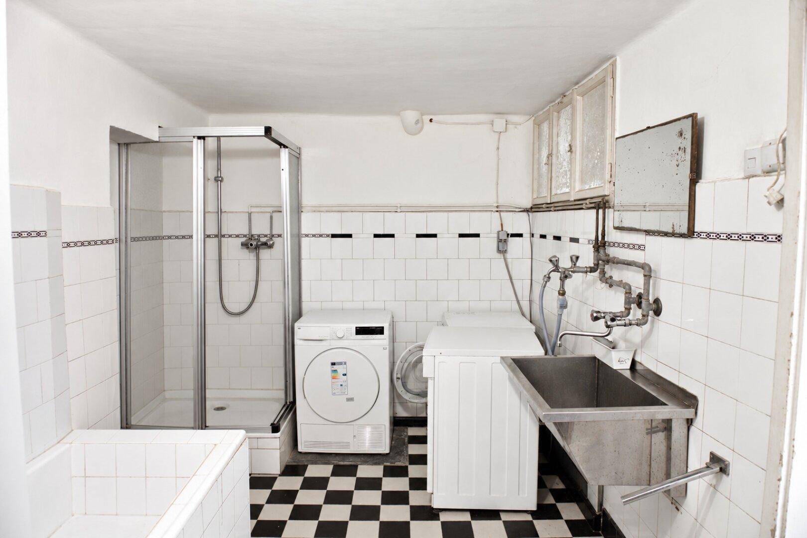 Hauswirtschaftsraum mit Duschkabine, Waschmaschine, Trockner und großem Waschbecken.