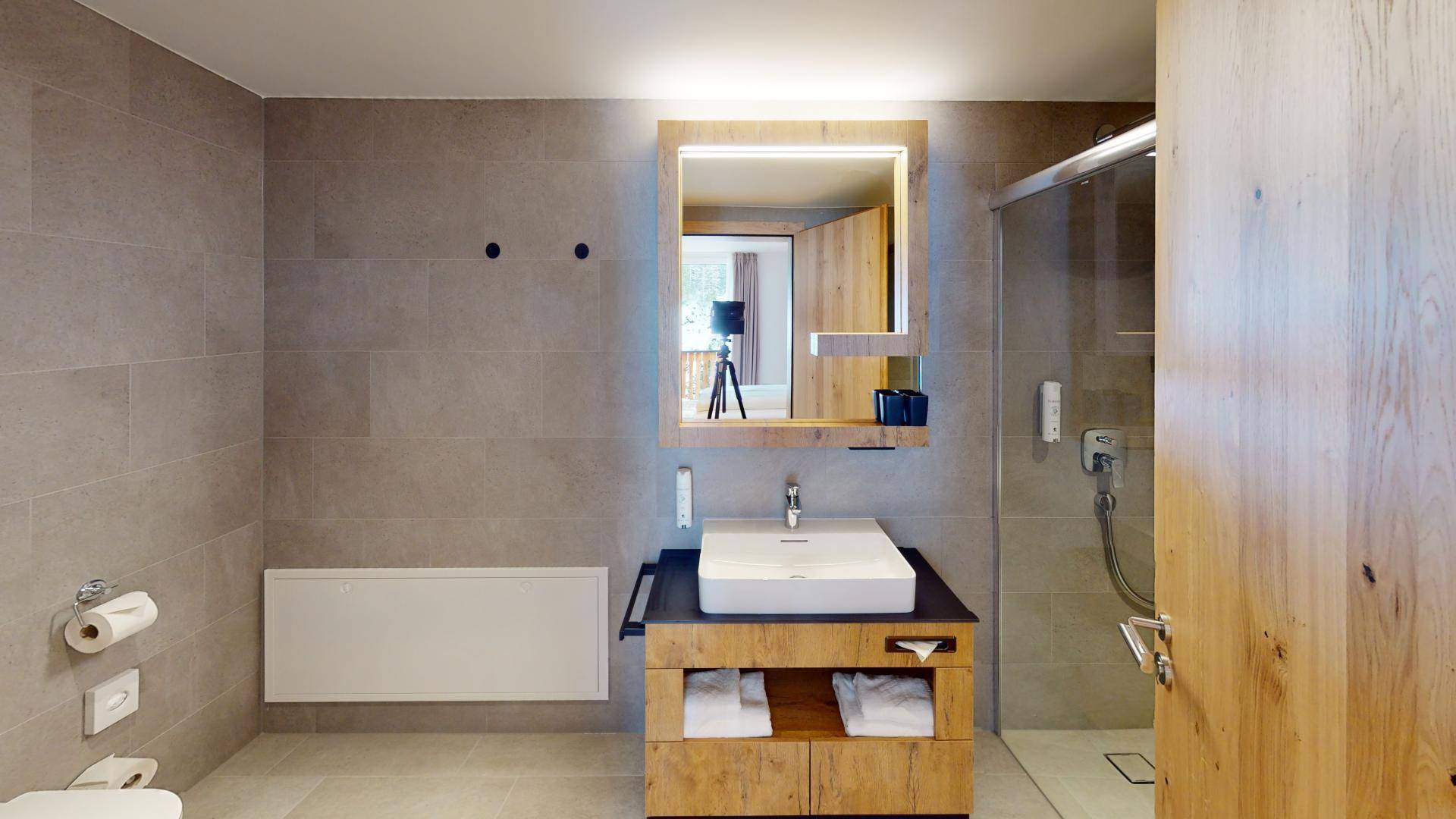 Modernes Badezimmer mit großformatigen Fliesen, Einzelwaschbecken und begehbarer Dusche.