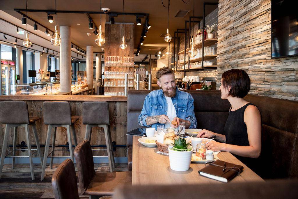 Gemütlicher Restaurantbereich mit Holzelementen, bequemen Sitzbänken und moderner Beleuchtung.