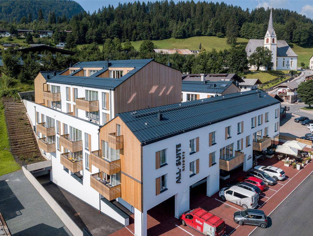 Moderne Wohnanlage in den Bergen mit Balkonen und umliegender Natur.