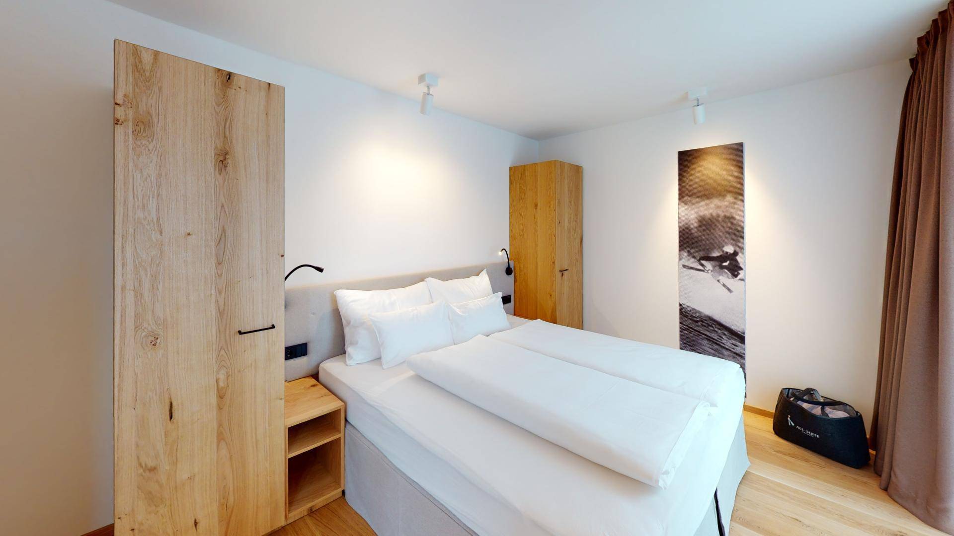 Modernes Schlafzimmer mit Holzboden, weiß gestrichenen Wänden und einem großen Holzschrank.