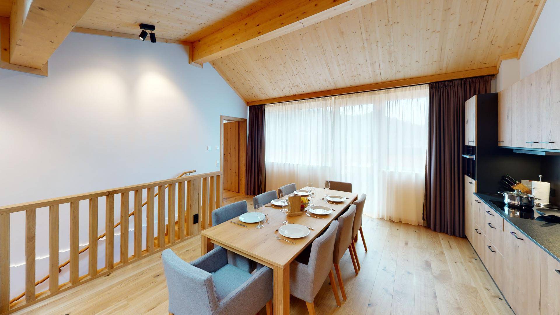 Heller Essbereich mit Holzboden, großer Fensterfront und integrierter Küchenzeile in modernem Design.