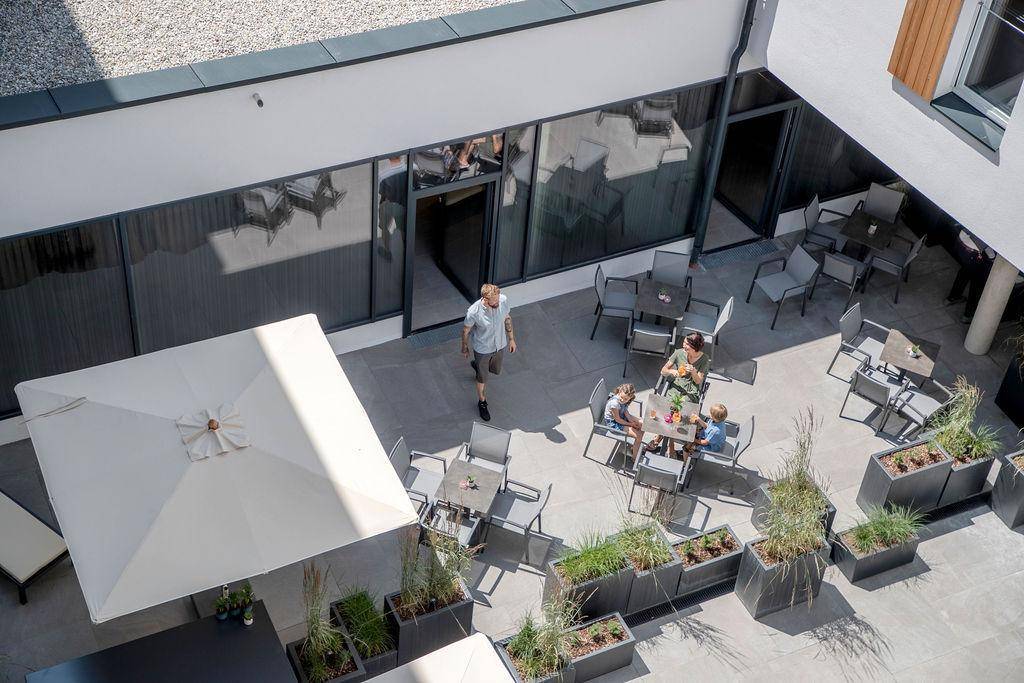 Begrünter Innenhof mit Sonnenschirm und Sitzgelegenheiten für entspannte Stunden.