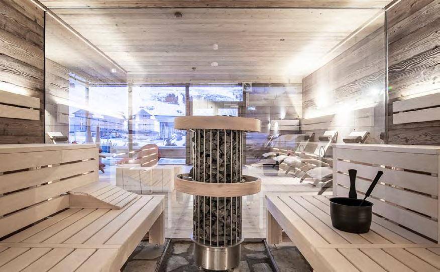 Heller Wellnessbereich mit Sauna, Holzbänken und Panoramablick auf die verschneite Landschaft.