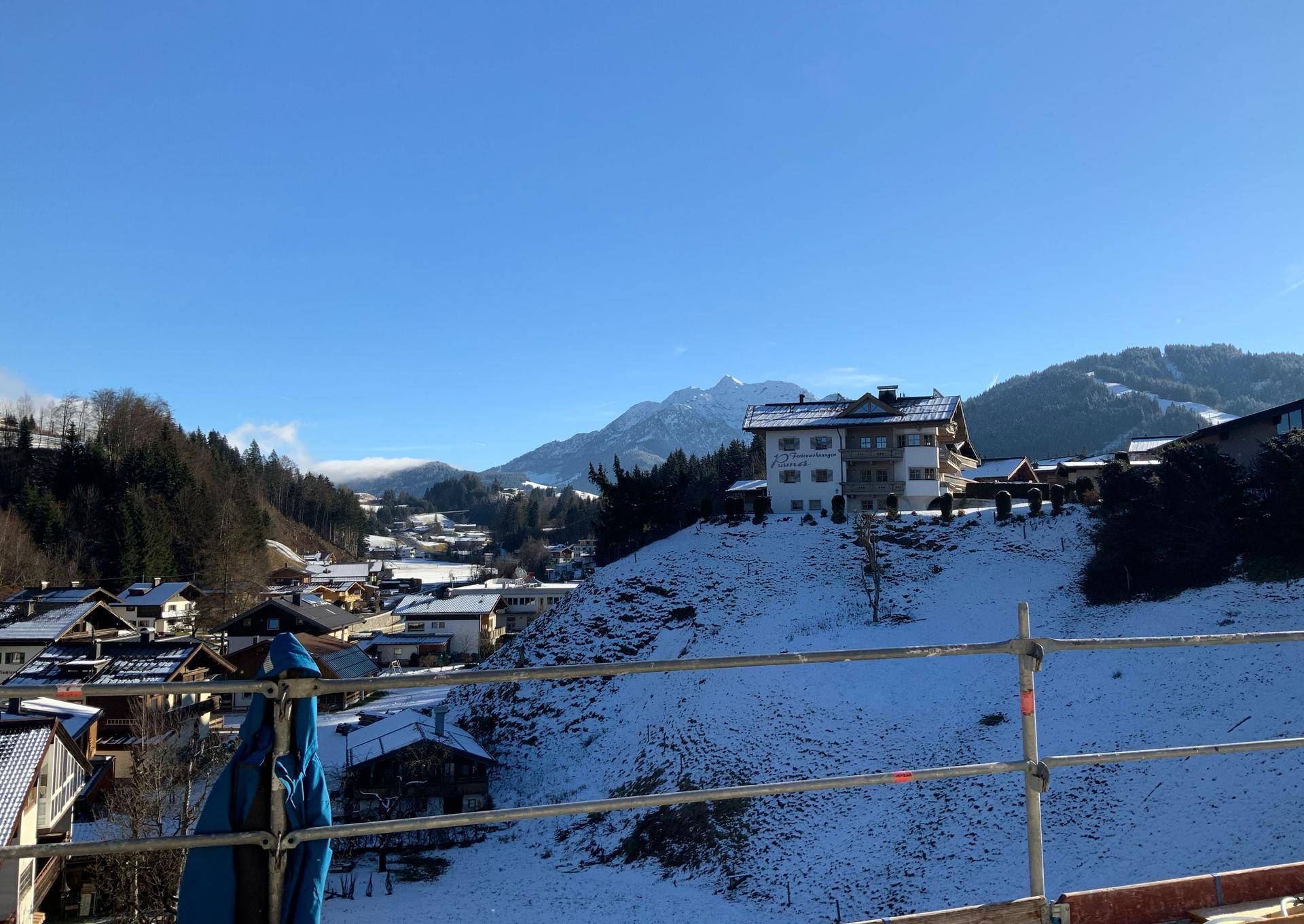 Winterliche Landschaft mit verschneiten Häusern und majestätischem Bergblick.