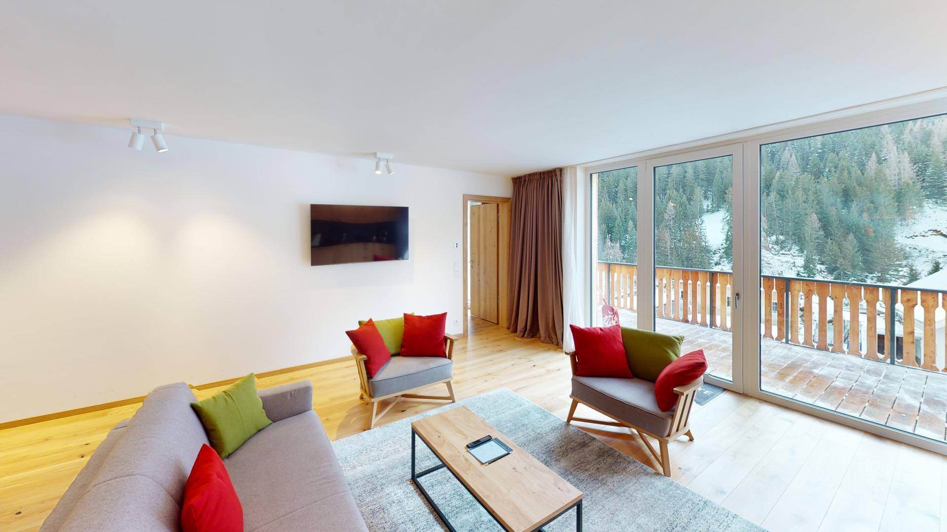 Helles Wohnzimmer mit Holzboden, bequemen Sofas und großen Fenstern mit Bergblick.