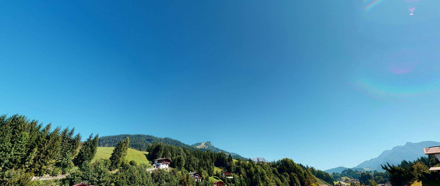 Malerischer Panoramablick auf dichte Wälder und grüne Berghänge unter strahlend blauem Himmel.