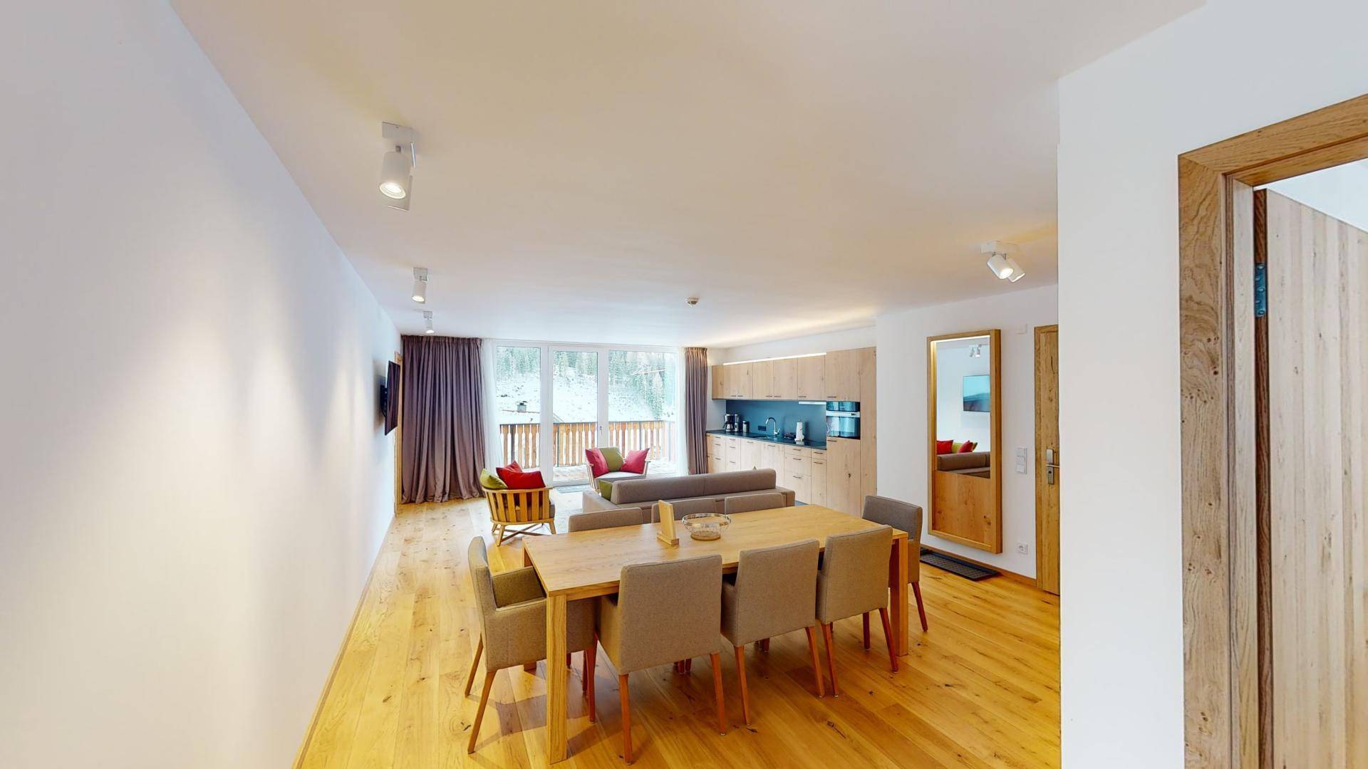 Heller offener Wohn- und Essbereich mit Holzboden und integrierter Küche in modernem Design.