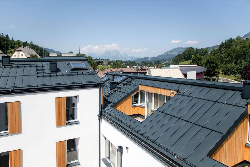 Dachansicht eines modernen Gebäudes mit dunklem Dach und Blick auf die Berglandschaft.