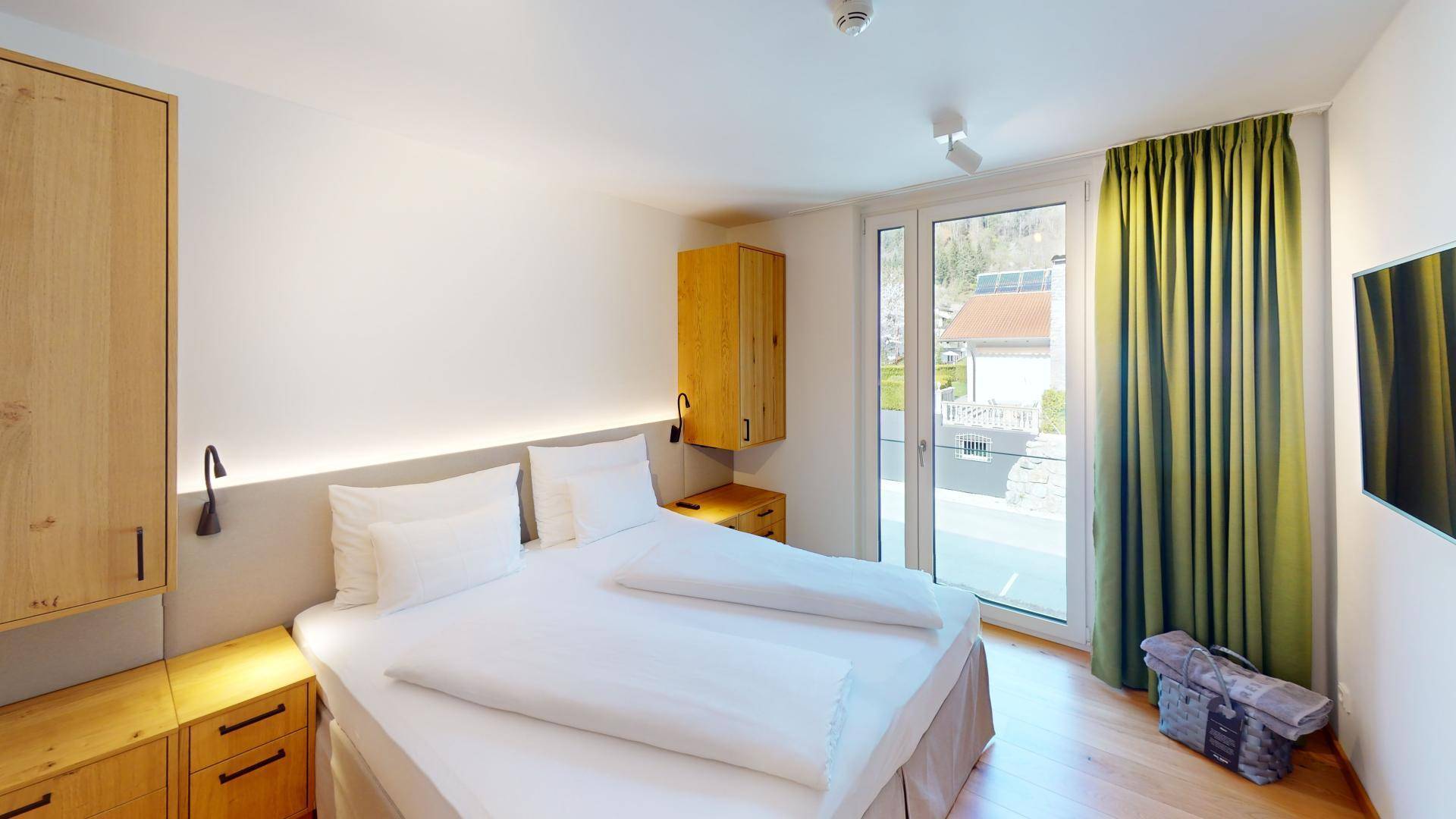 Schlafzimmer mit Doppelbett, Holzboden und Balkonzugang, bietet einen Blick auf die Umgebung.