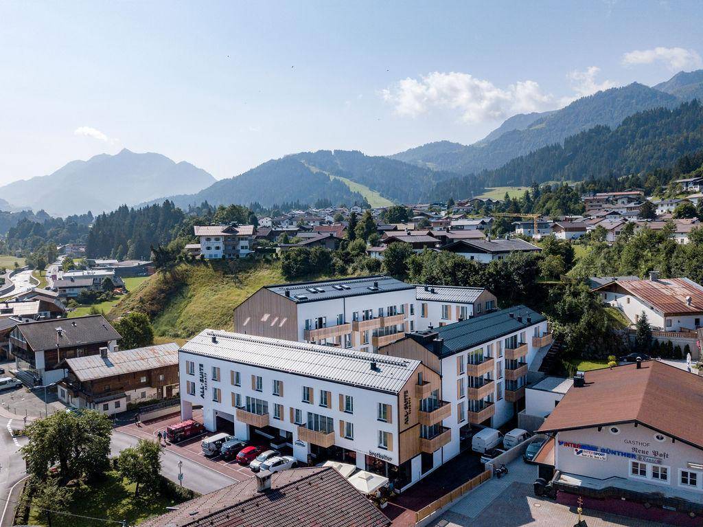 Panoramablick auf die moderne Wohnanlage eingebettet in eine Berglandschaft.