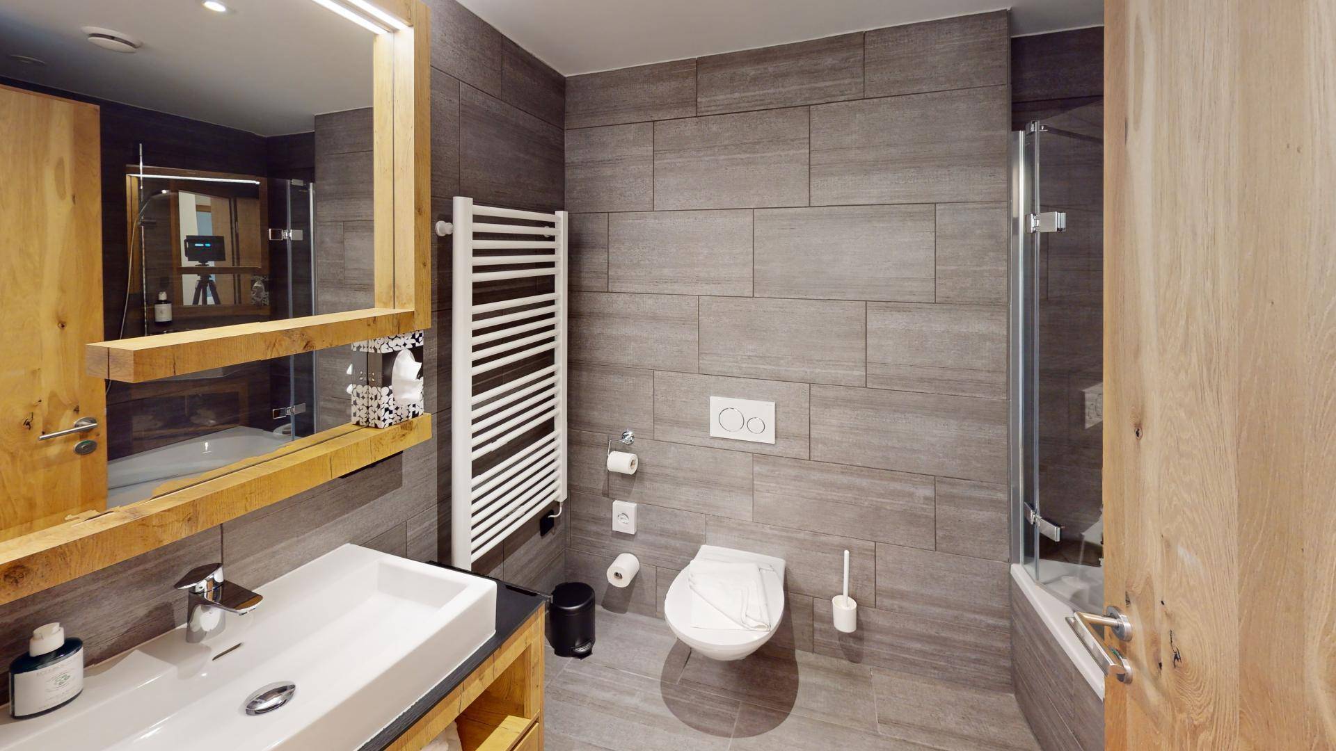 Modernes Badezimmer mit Dusche, WC, Waschtisch und beheiztem Handtuchhalter.