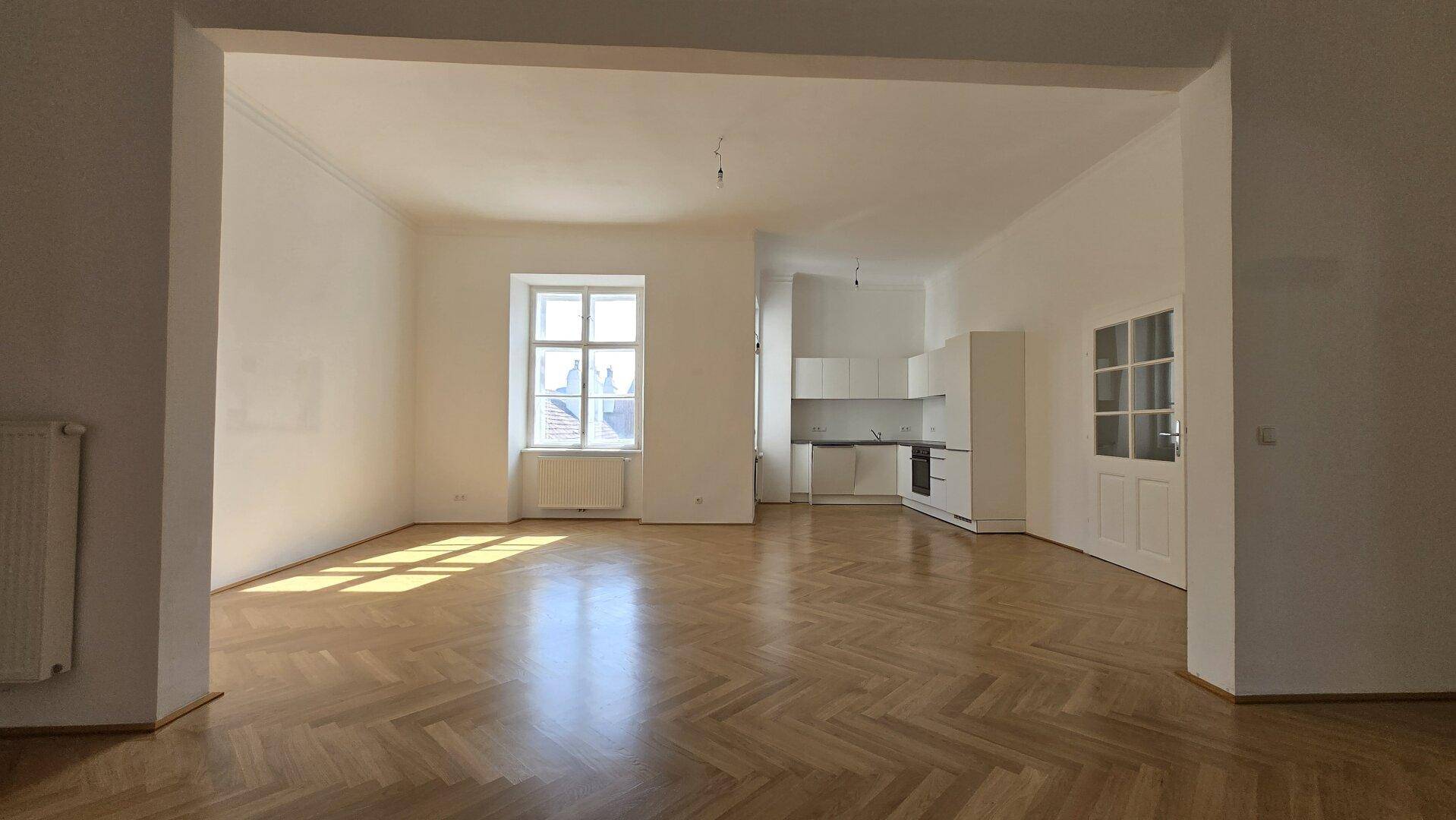 Heller Wohnbereich mit Parkettboden und offener Verbindung zur Küche.