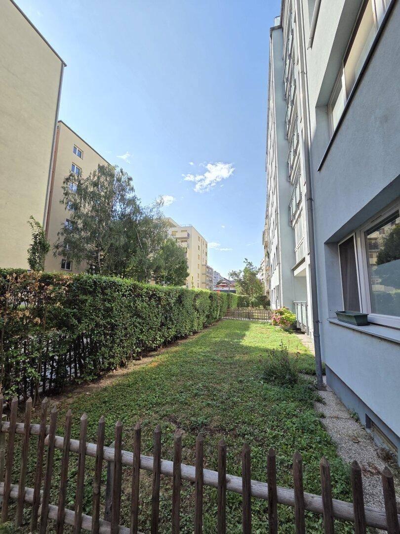 Gepflegter Gemeinschaftsgarten mit Rasenfläche und Hecke zwischen Wohngebäuden.