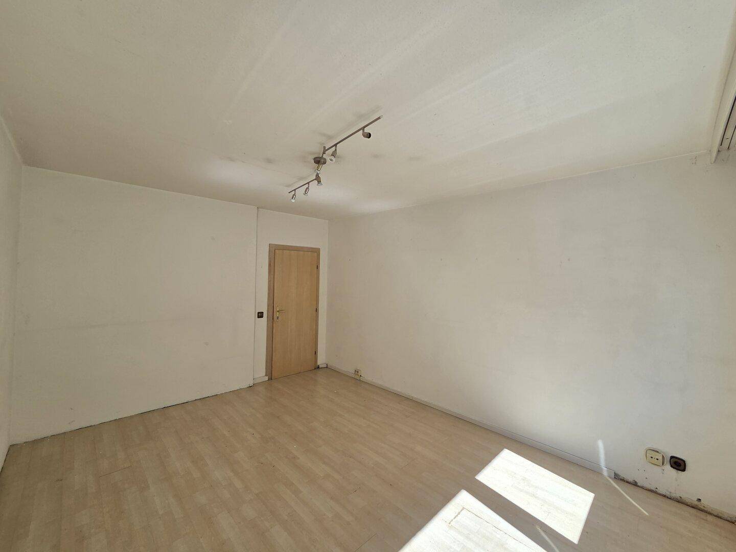 Leeres Schlafzimmer mit Laminatboden und einer Holztür, bereit zur individuellen Gestaltung.