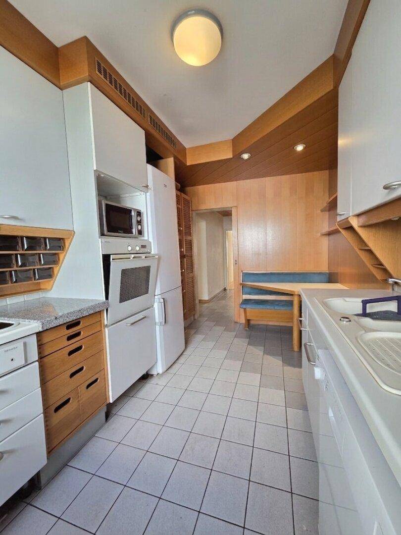 Traditionelle Küche mit weißen Schränken, Holzelementen und Fliesenboden, mit Essbereich.