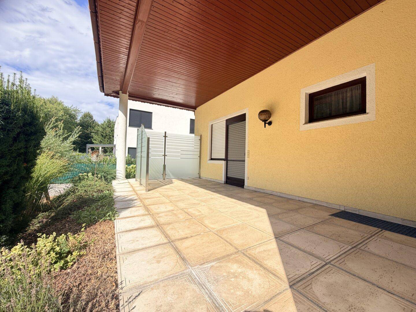 Geflieste Terrasse mit Überdachung und direktem Zugang zum Haus, ideal für entspannte Stunden.