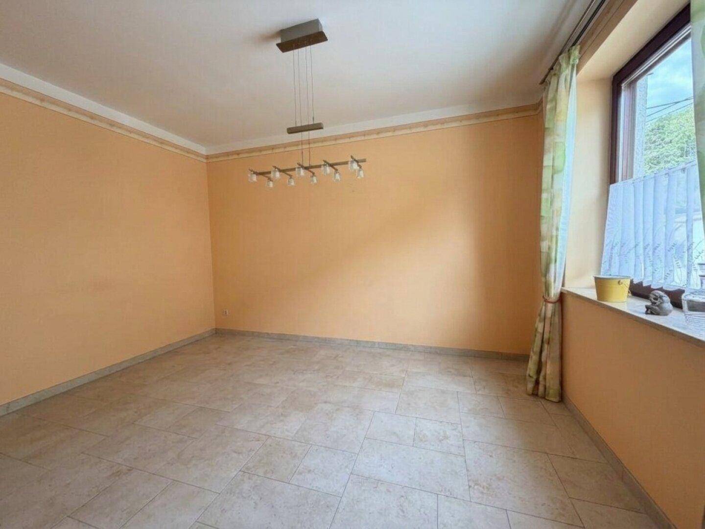 Heller Essbereich mit Fliesenboden und Fenster, bereit zur individuellen Gestaltung und Nutzung.