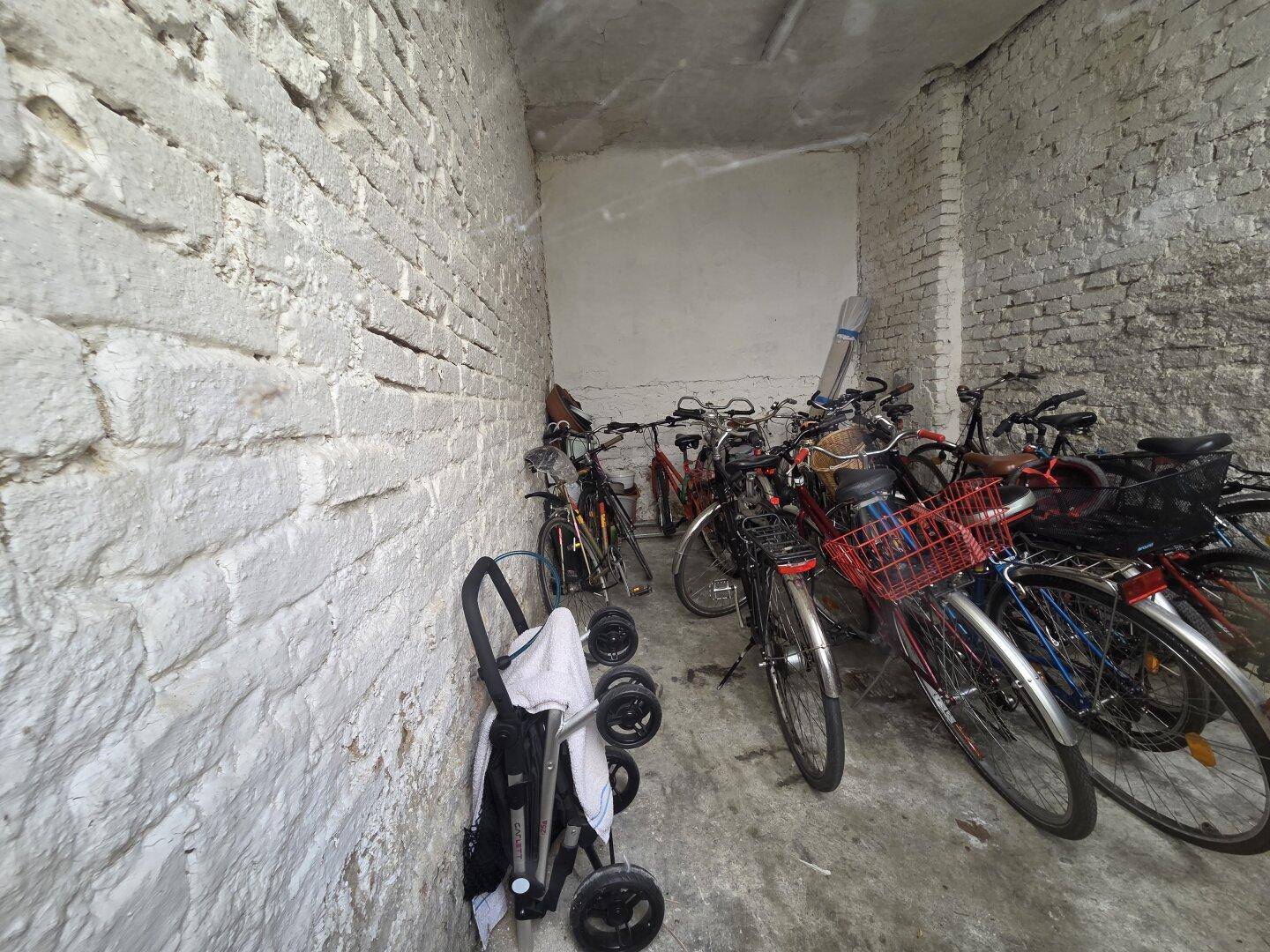 Gemeinschaftlicher Fahrradraum im Keller mit vielen Fahrrädern und weiß gestrichenen Ziegelwänden.