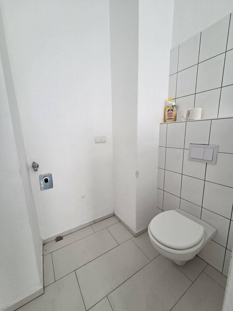 Separates WC mit Wand-WC und weißen Fliesen, praktisch und funktional.