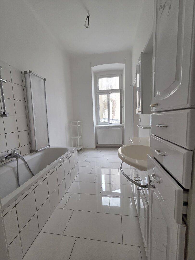 Helles Badezimmer mit Badewanne, Waschbecken und modernen weißen Fliesen.