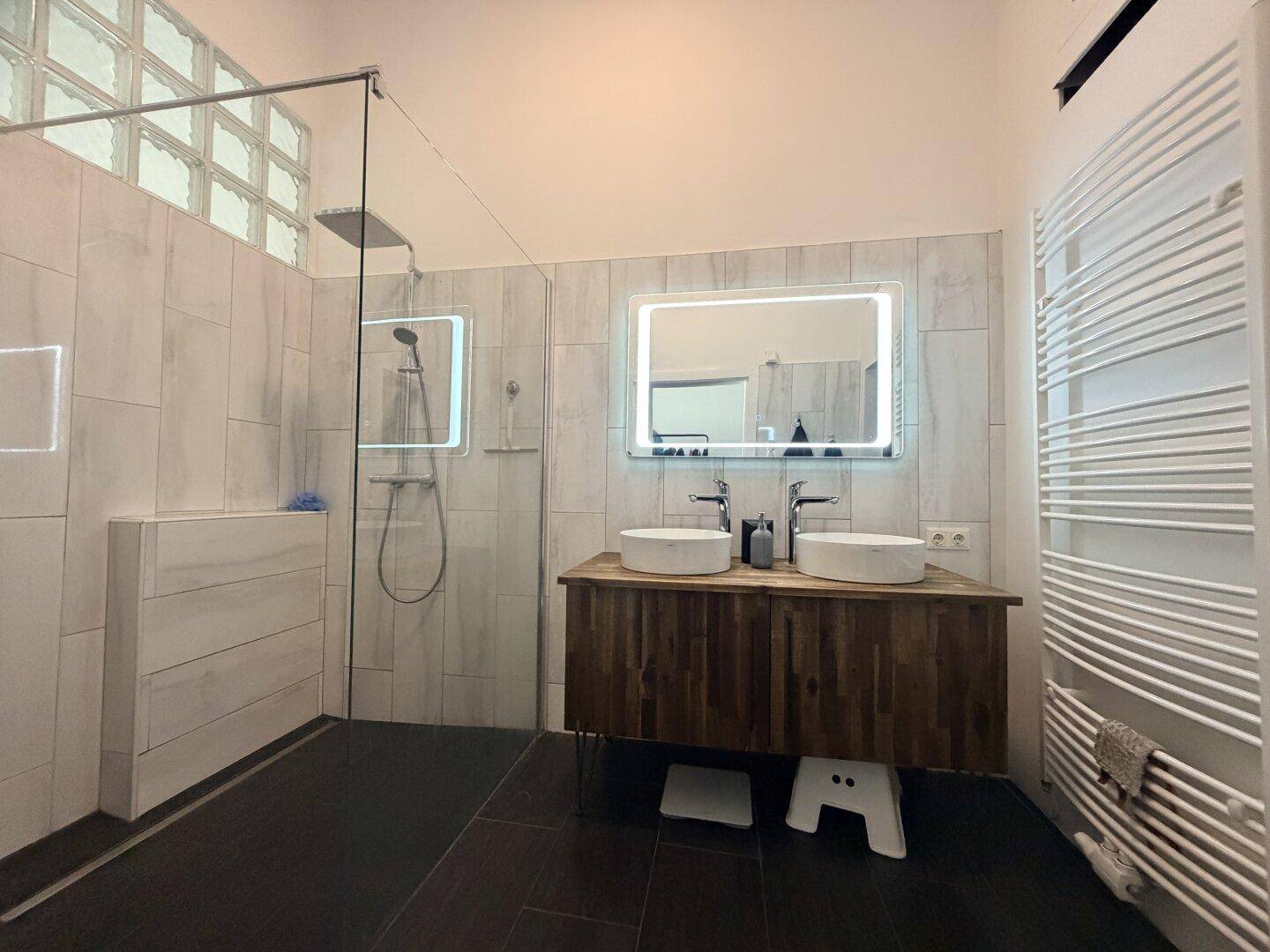 Modernes Badezimmer mit begehbarer Dusche, Doppelwaschbecken und beheiztem Handtuchhalter.
