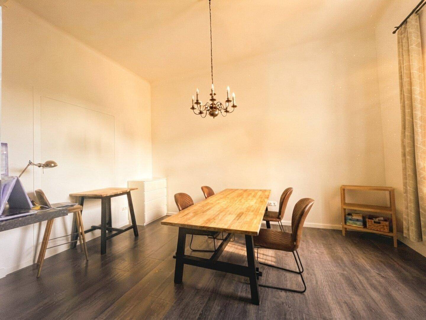 Geräumiges Esszimmer mit Holztisch, Lederstühlen und dunklem Laminatboden.