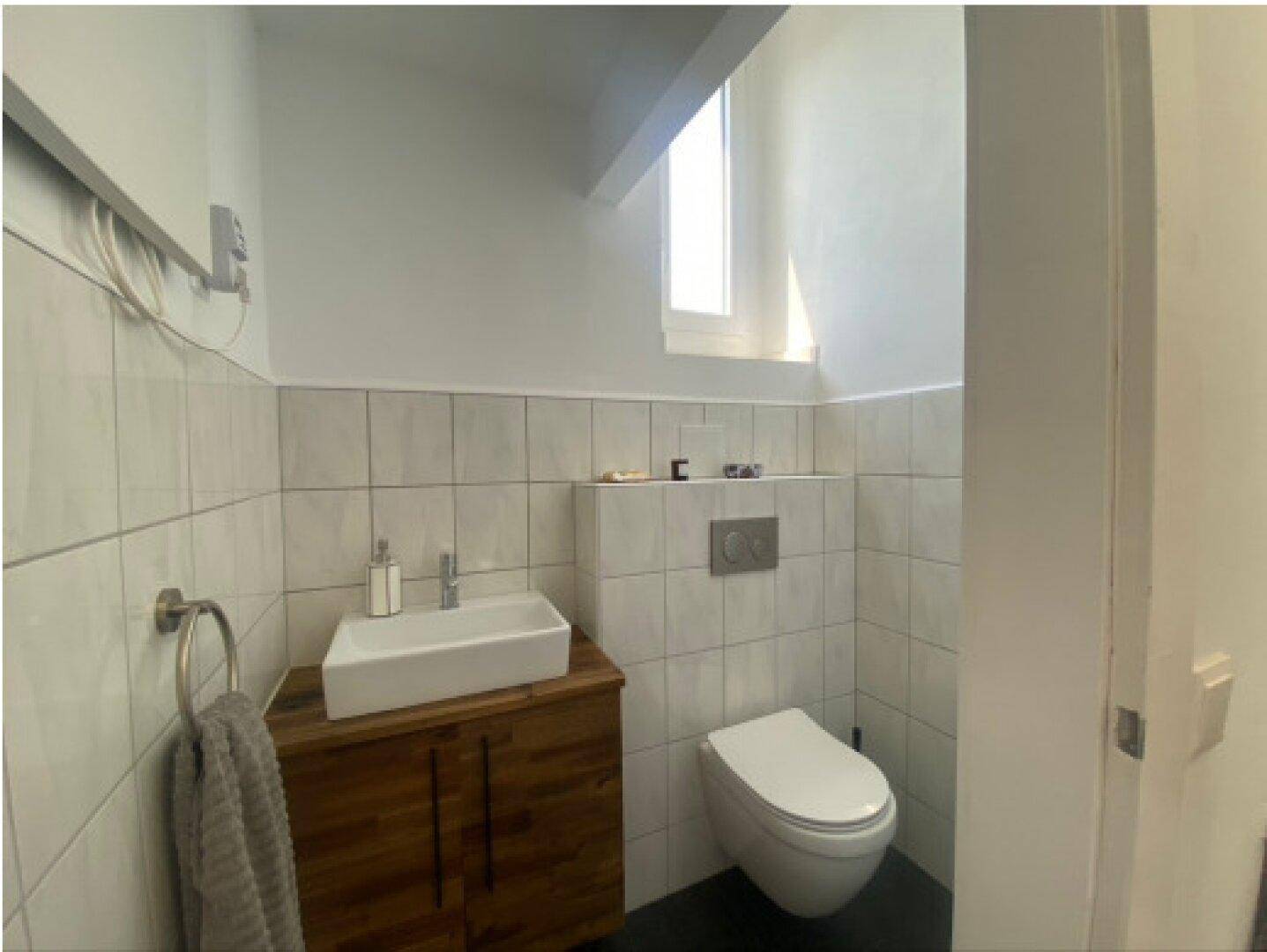 Modernes Gäste-WC mit wandhängender Toilette und kleinem Waschbecken.